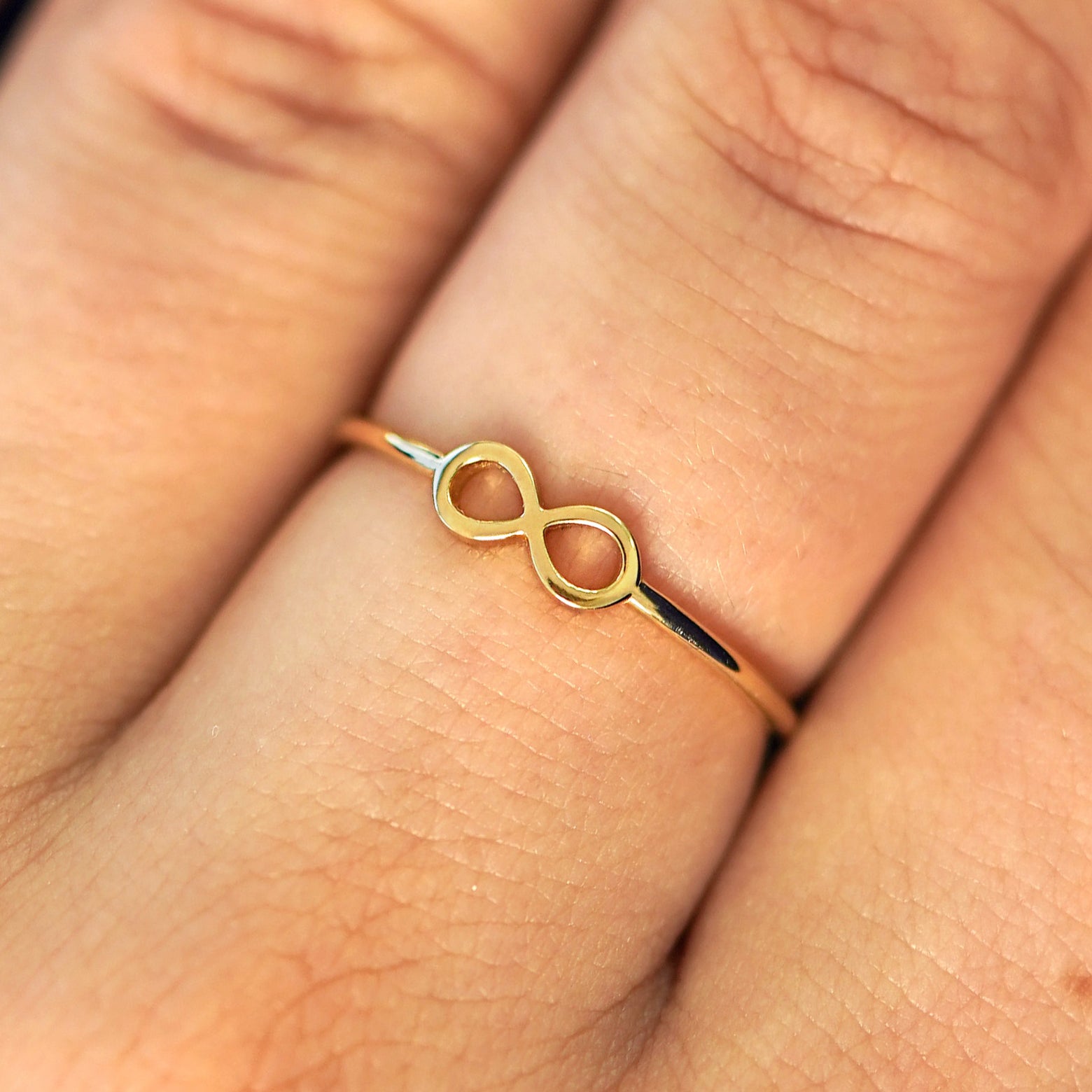 Close up view of a model's fingers wearing a 14k gold Infinity Ring