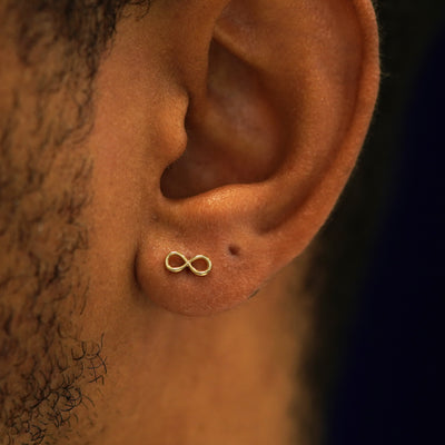 A model's ear wearing a 14k yellow gold Infinity Stud Earring