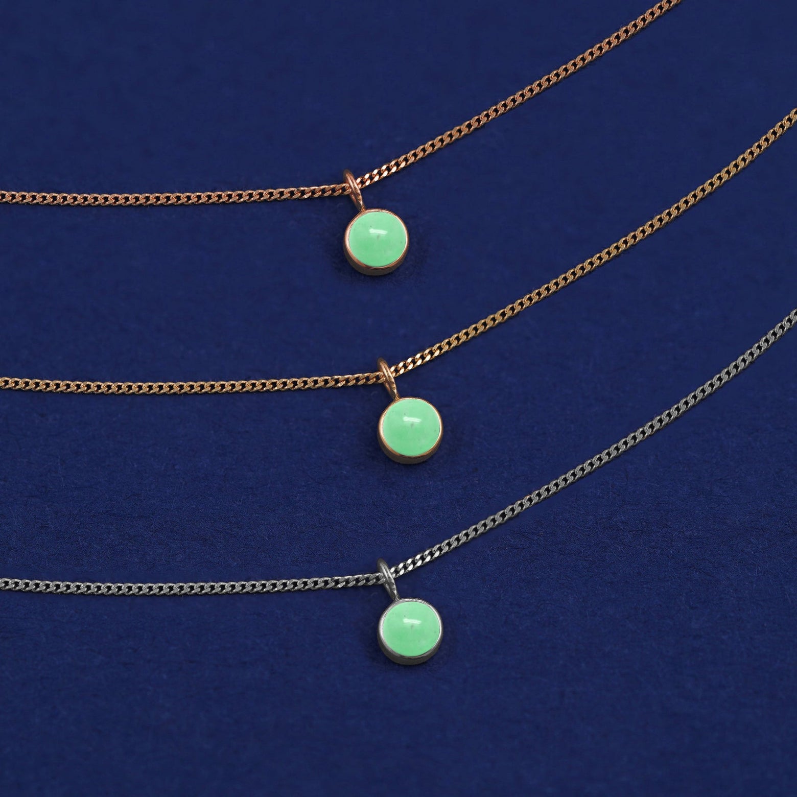 Three versions of the Jade Necklace shown in options of yellow, white and rose gold on a dark blue background