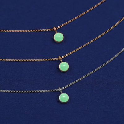 Three versions of the Jade Necklace shown in options of yellow, white and rose gold on a dark blue background