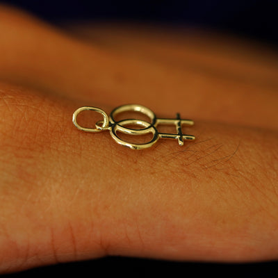 A 14k solid gold Lesbian Symbol Charm for chain balancing on the back of a model's finger