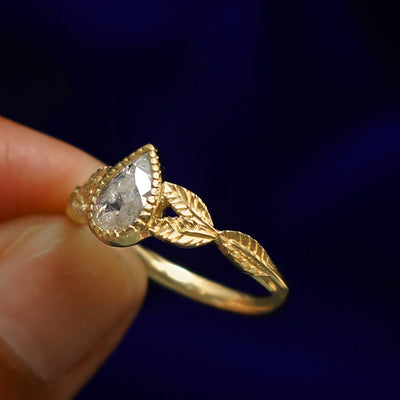 A model holding a Pear Salt and Pepper Diamond Leaves Ring tilted to show the inside of the ring