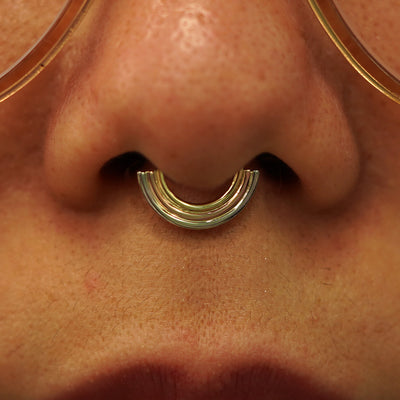 Close up view of a model's nose wearing a solid gold Rainbow Septum