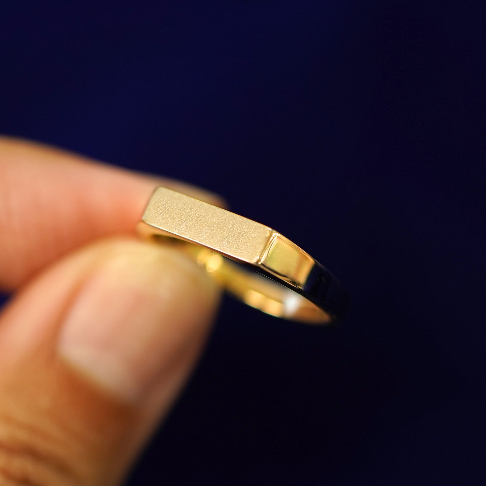 A model holding a Rectangular Signet Ring tilted to show the detail of the top of the ring
