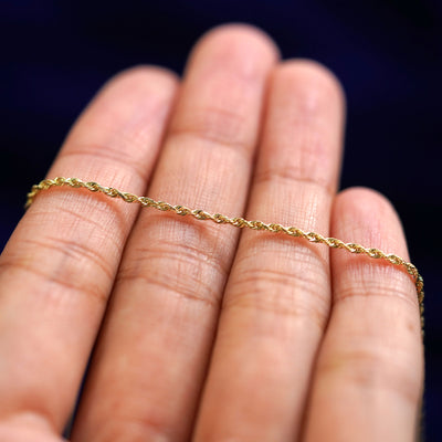 A yellow gold Rope Anklet resting on a model's fingers