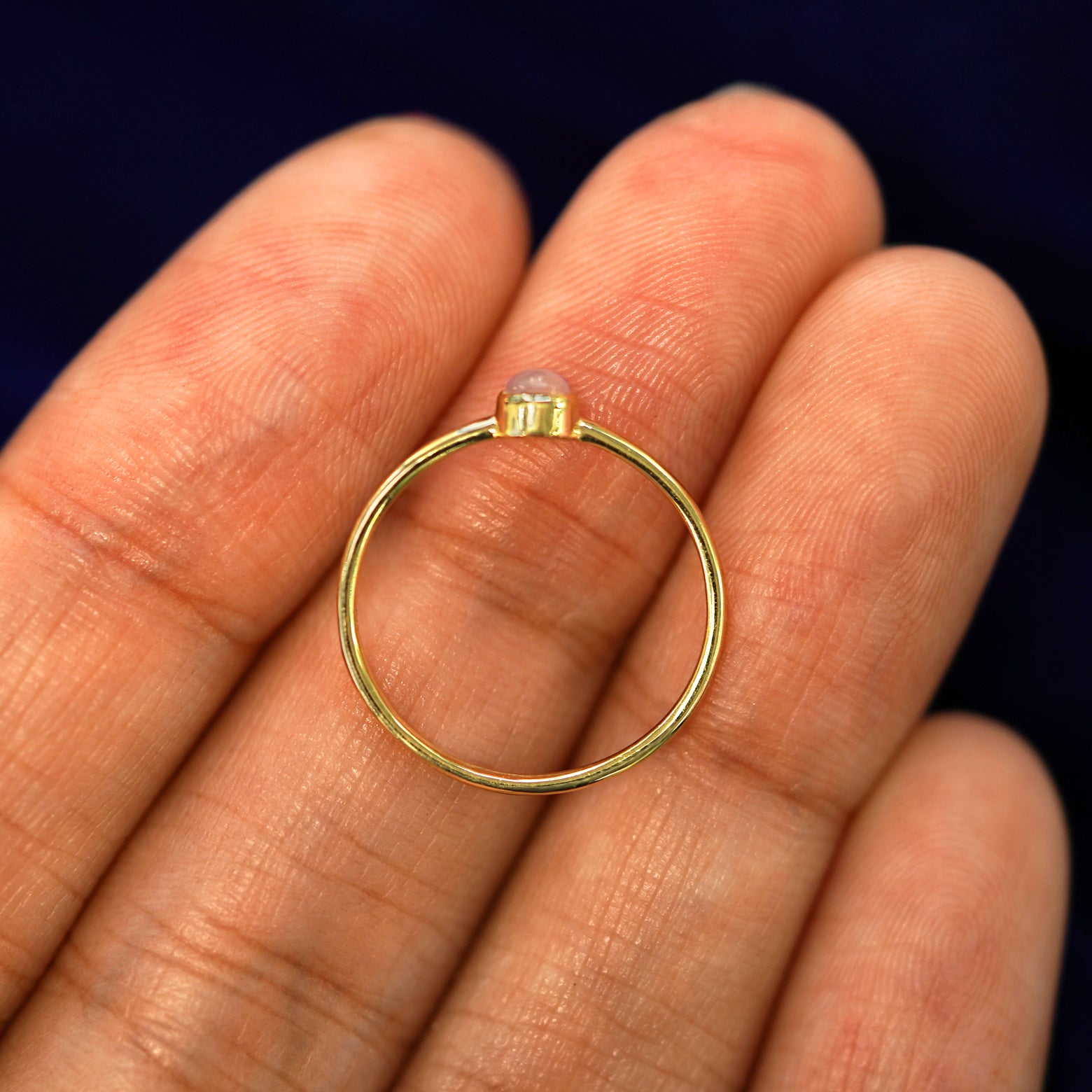 A 14k yellow gold Rose Quartz Ring laying in on a models fingers to show the thickness of the band