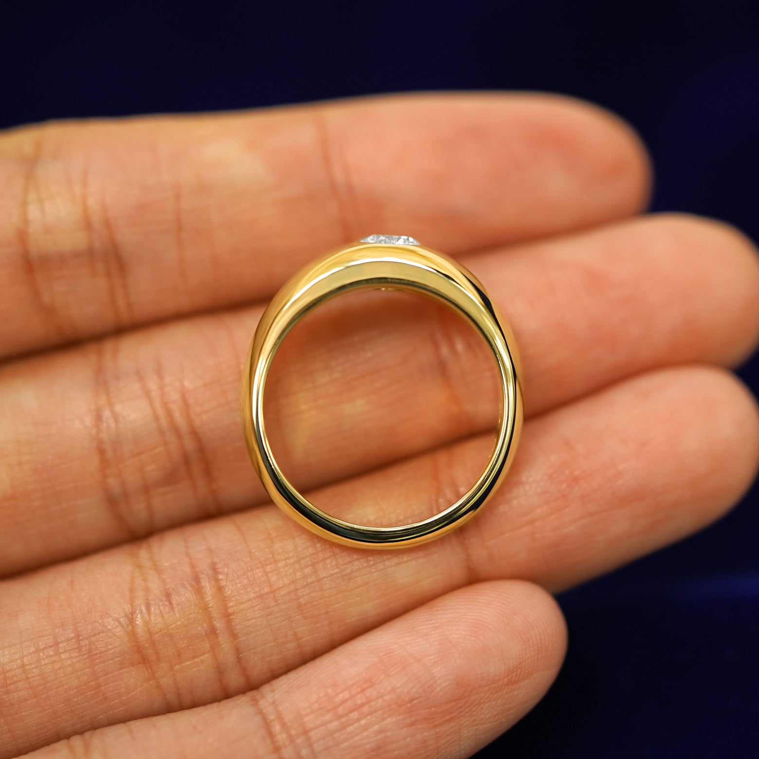 An Round Lab Diamond Puffy Signet Ring laying in a model's hand to show the thickness of the band