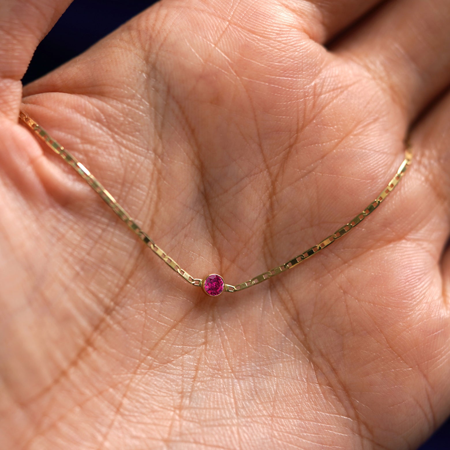 A yellow gold Ruby Bracelet draped on a model's palm