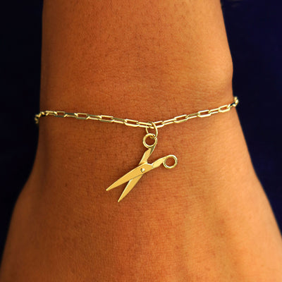 Close up view of a model's wrist wearing a yellow gold Scissors Charm on a Butch Chain Bracelet