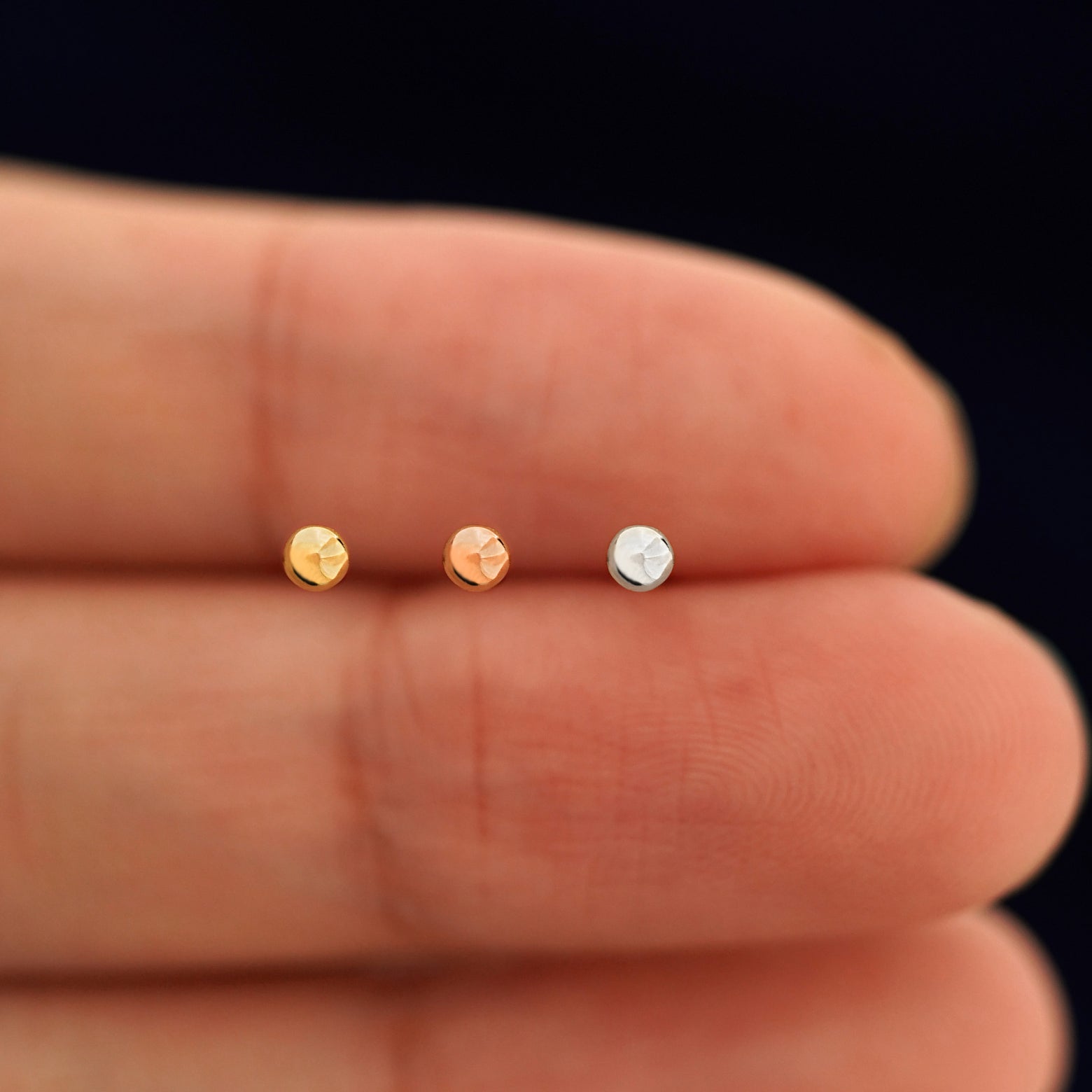 Three versions of the Small Ball Flat Back showing options of yellow, rose, and white gold in between a model's fingers