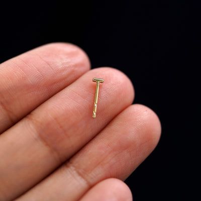 A yellow gold Small Line Earring laying facedown on a model's fingers to show the underside view