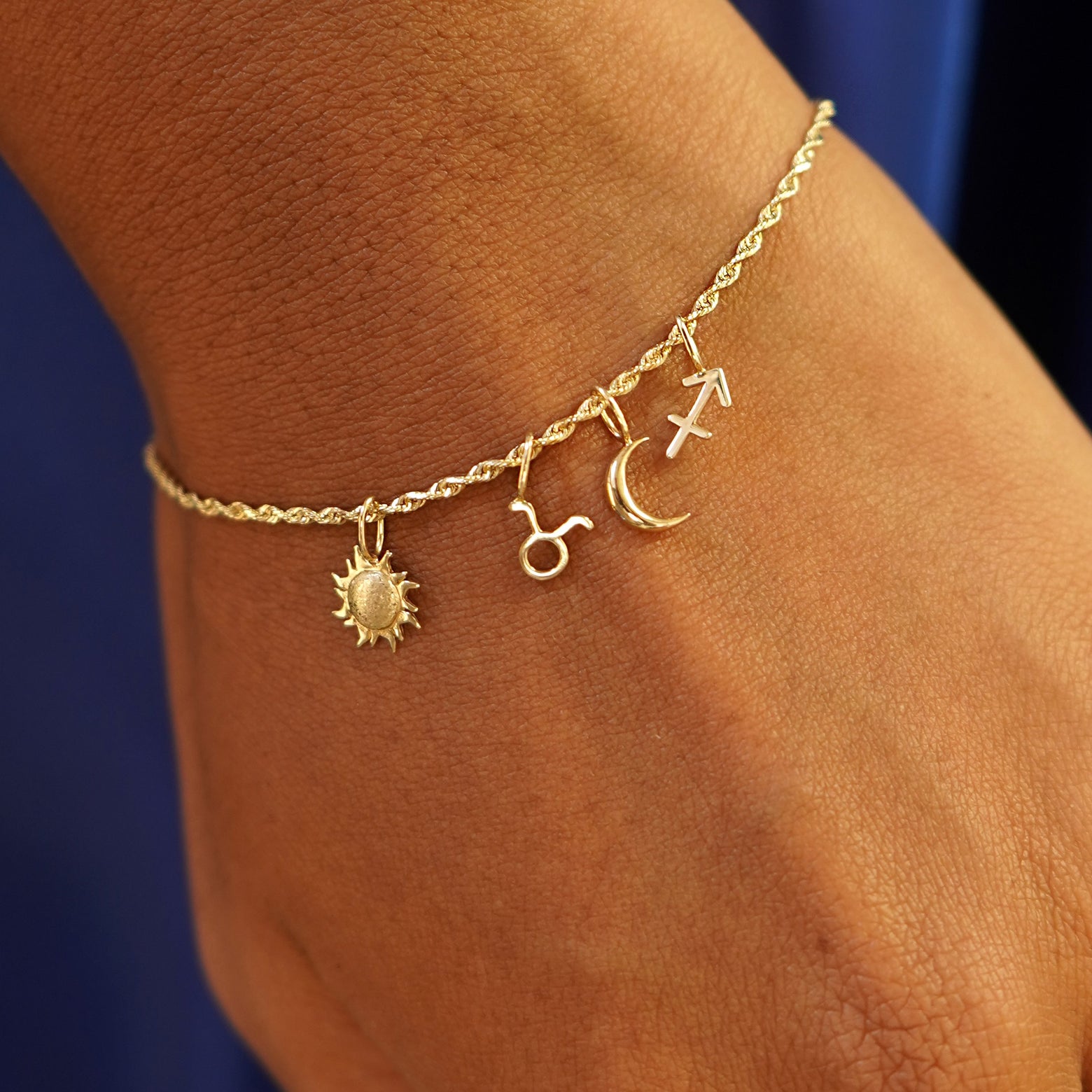 Close up view of a model's wrist wearing a Rope Bracelet with a Sun, a Moon, and two Horoscope Charms