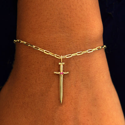 Close up view of a model's wrist wearing a yellow gold Sword Charm on a Butch Chain Bracelet