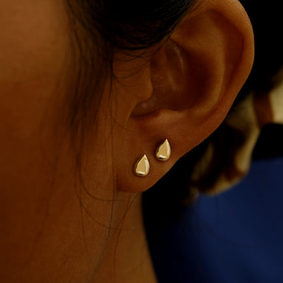 A model's ear wearing a pair of Teardrop stud earrings in two different lobe piercings on the same ear