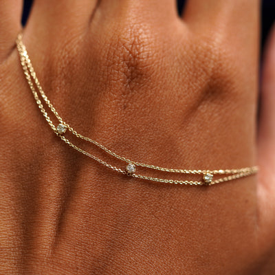 A solid gold 3 Diamond Cable Bracelet resting on the back of a model's hand