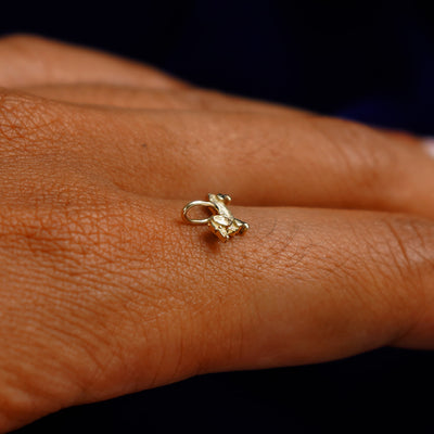 A 14k yellow gold Dog Charm for chain balancing on the back of a model's finger