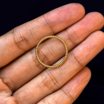 A yellow gold Rope Ring in a model's hand showing the thickness of the band