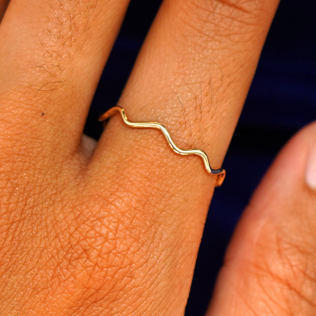Close up view of a model's fingers wearing a 14k yellow gold Wave Ring