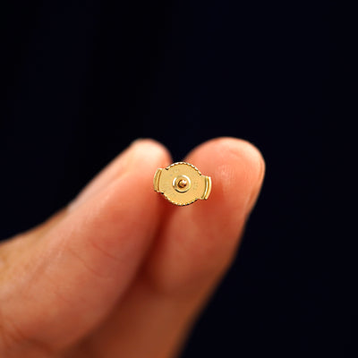 A 14k gold Salt and Pepper Diamond Pressure Lock Earring held backward between a model's fingers to show the backing