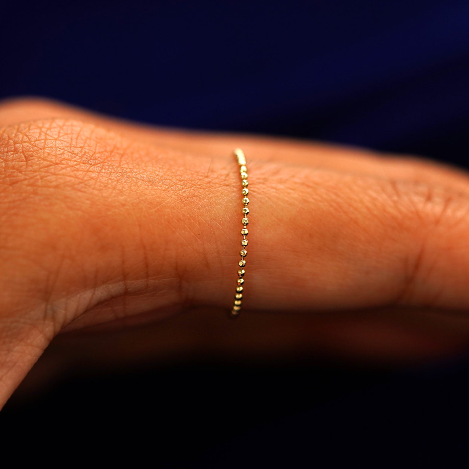 Side view of a Bead Chain Ring on a model's finger