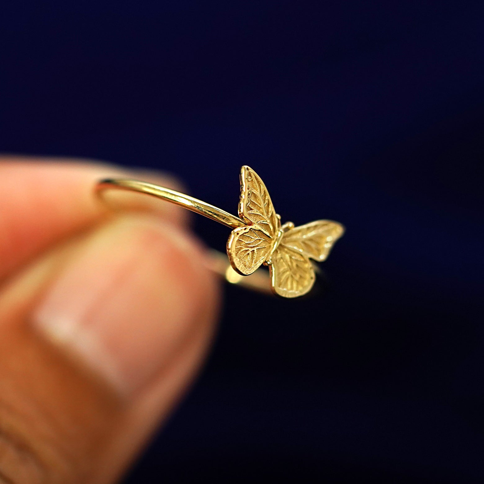 A model holding a Butterfly Ring tilted to show the side of the ring