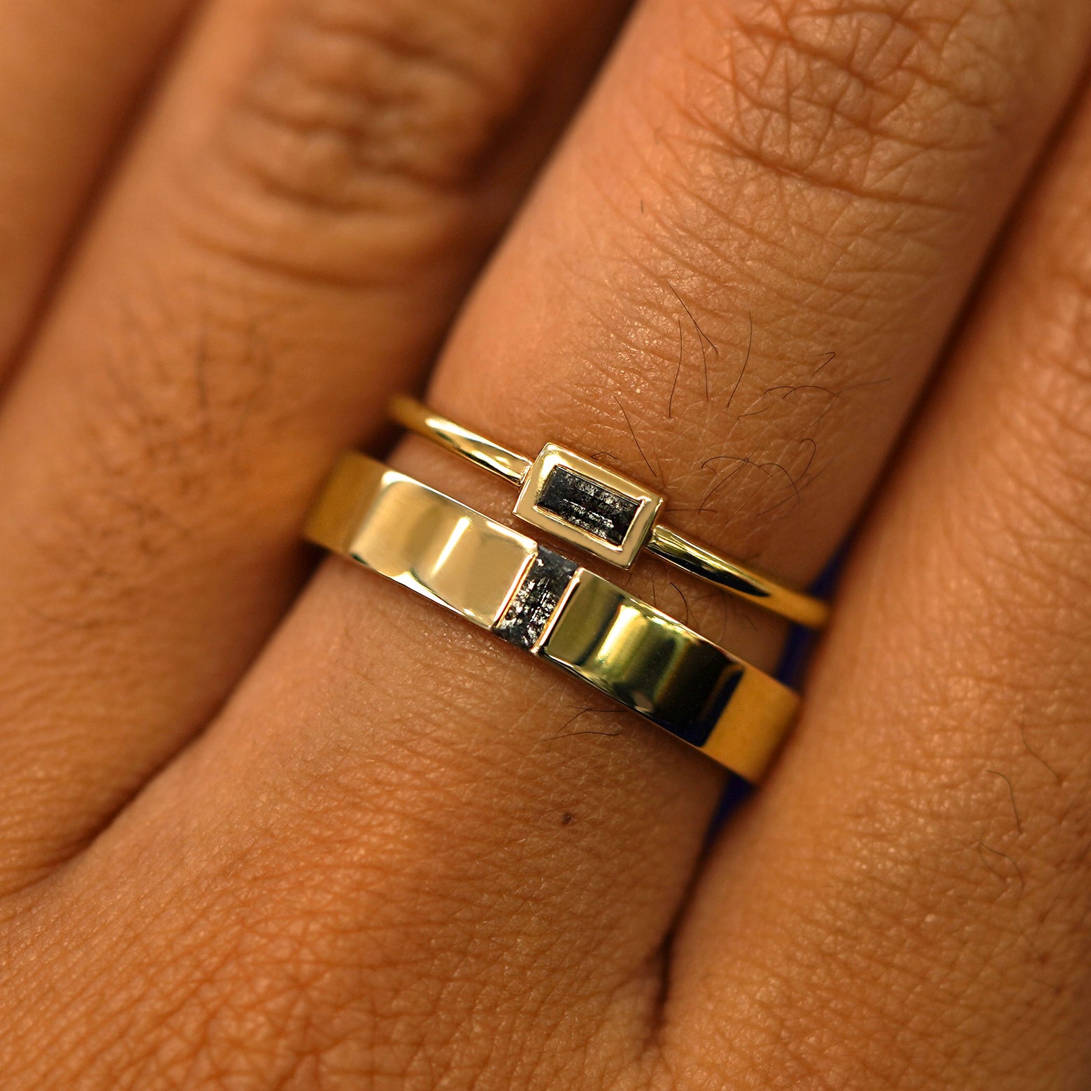 A model wearing a Salt and Pepper Baguette Diamond Band and a Baguette Salt and Pepper Diamond Ring stacked on one finger