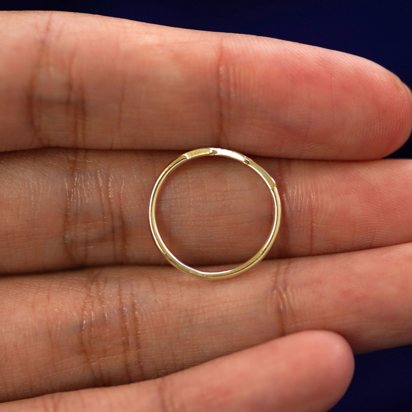 A yellow gold Lightning Bolt Ring in a model's hand showing the thickness of the band