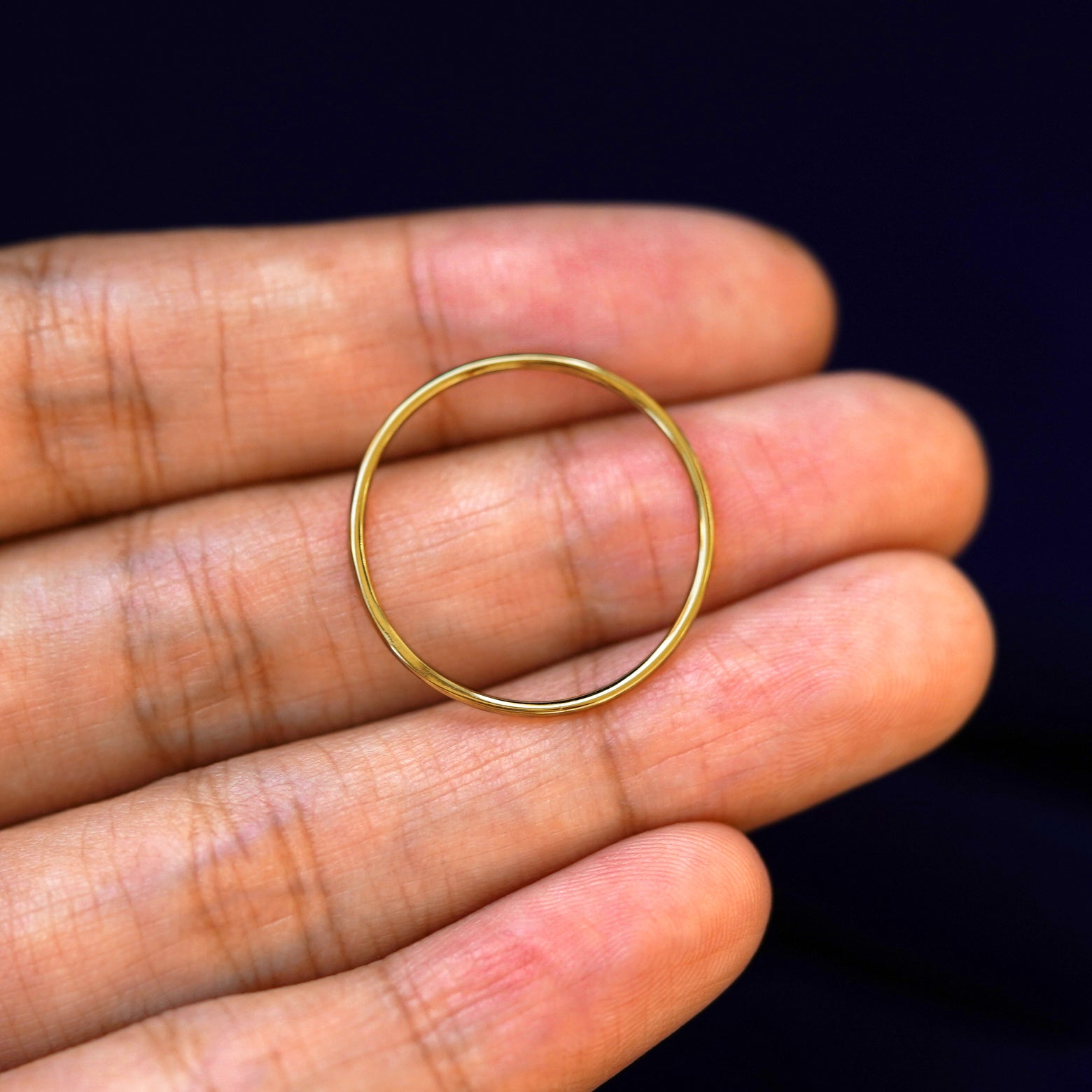 A yellow gold Line Ring in a model's hand showing the thickness of the band