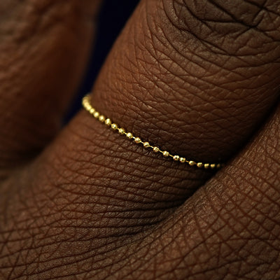 Close up view of a model's fingers wearing a 14k yellow gold Bead Chain Ring
