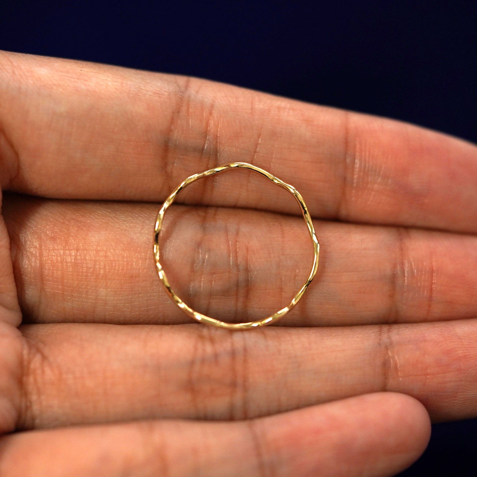 A yellow gold Wave Ring in a model's hand showing the thickness of the band