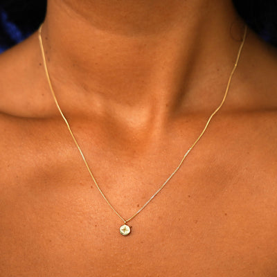 Close up view of a model's neck wearing a solid yellow gold Star Disk Necklace