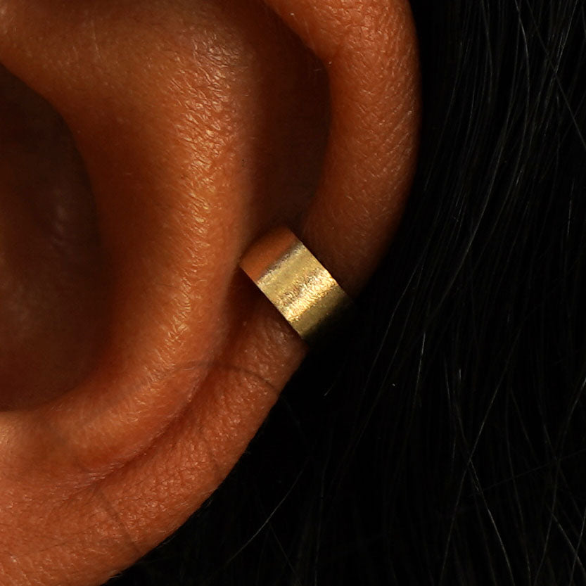 Close up view of a model's ear wearing a 14k gold Stardust Thick Cuff