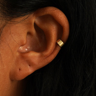 A model's ear wearing a 14k yellow gold Stardust Thick Cuff
