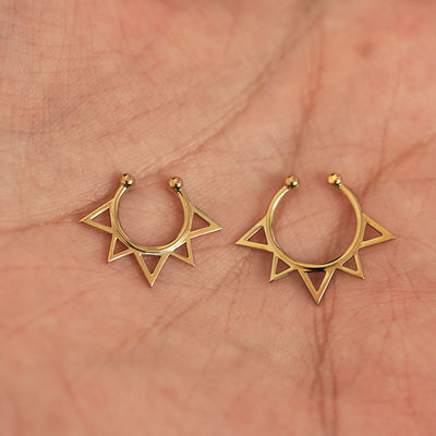 A model's palm holding two versions of the non-pierced Sun Septum showing the 8mm and 10mm sizes