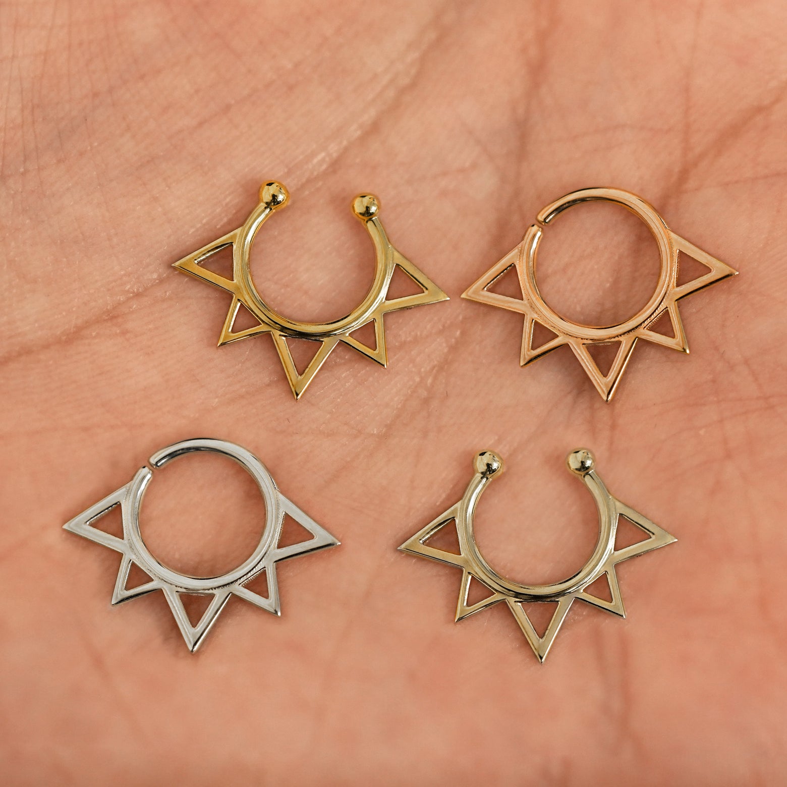 Four versions of the Sun Septum shown in options of yellow, white, rose and champagne gold in a model's palm