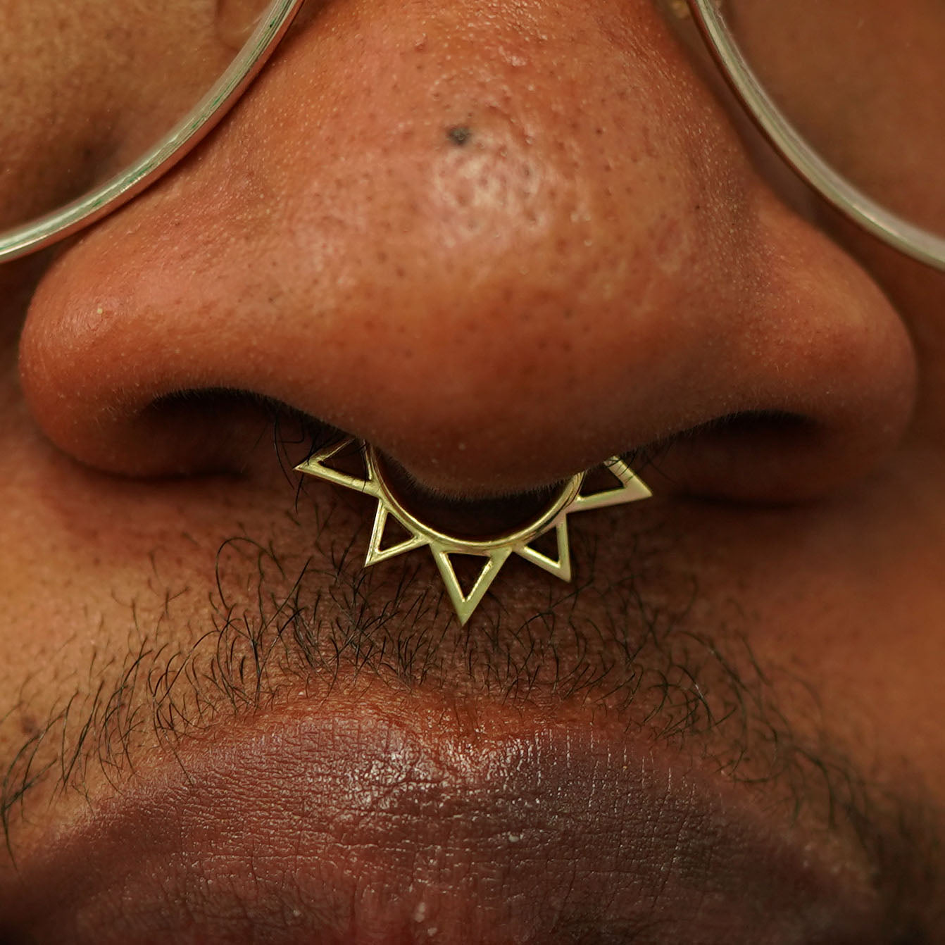 Close up view of a model's nose wearing a 14k yellow gold Sun Septum