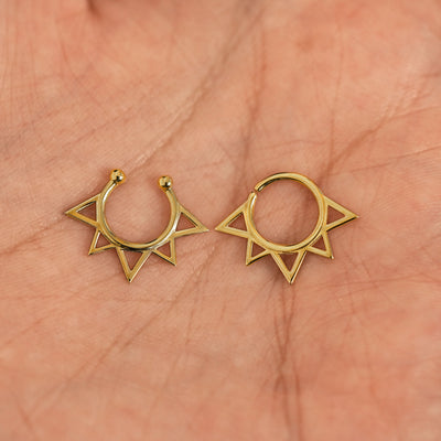 Two 14k solid gold Sun Septum rings show in options of Non-Pierced and Pierced resting in the palm of a model's hand