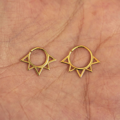 A model's palm holding two versions of the pierced Sun Septum showing the 8mm and 10mm sizes