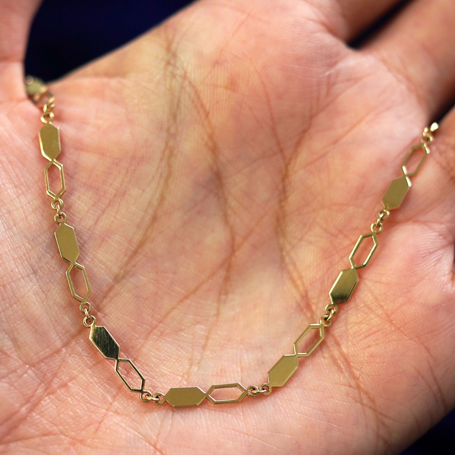 A yellow gold Tanlah Chain draped on a model's palm
