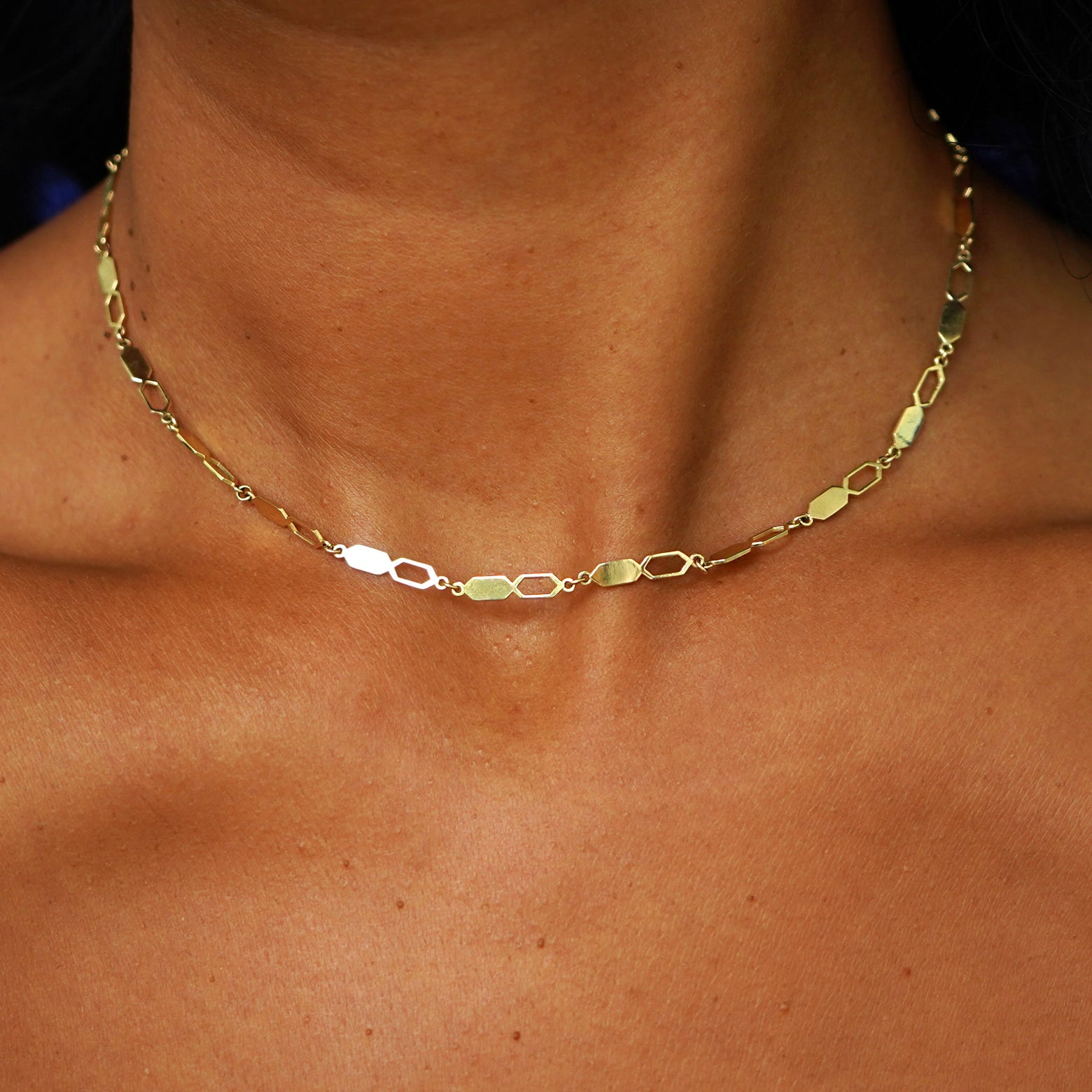 A model's neck wearing a solid 14k yellow gold Tanlah Chain