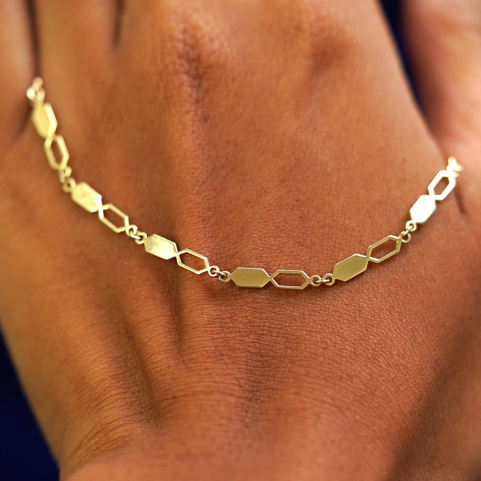 A solid gold Tanlah Chain resting on the back of a model's hand