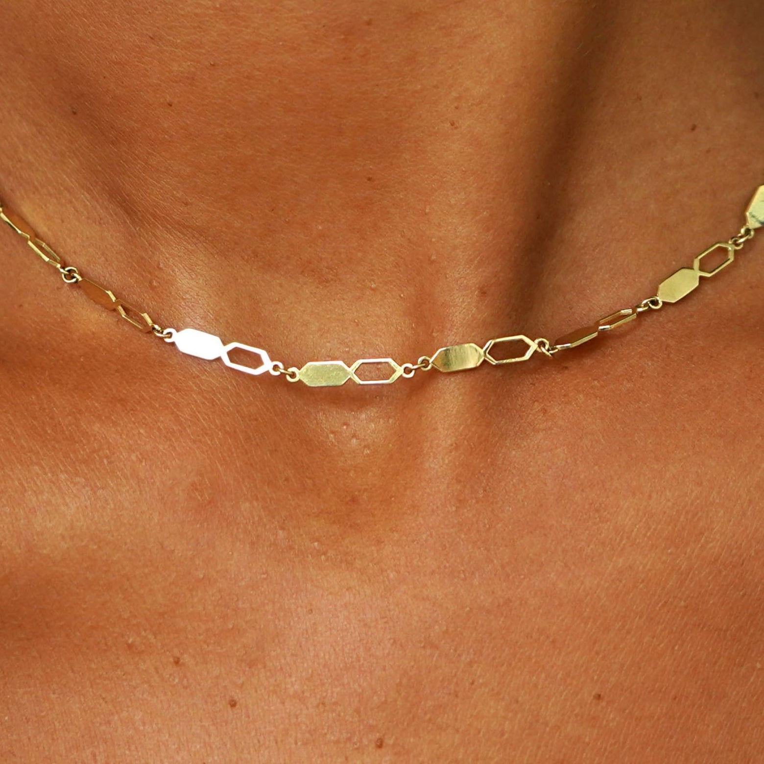 Close up view of a model's neck wearing a solid 14k yellow gold Tanlah Chain