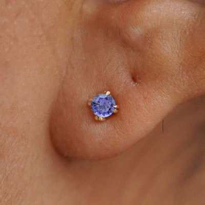 Close up view of a model's ear wearing a 14k yellow gold Tanzanite Earring