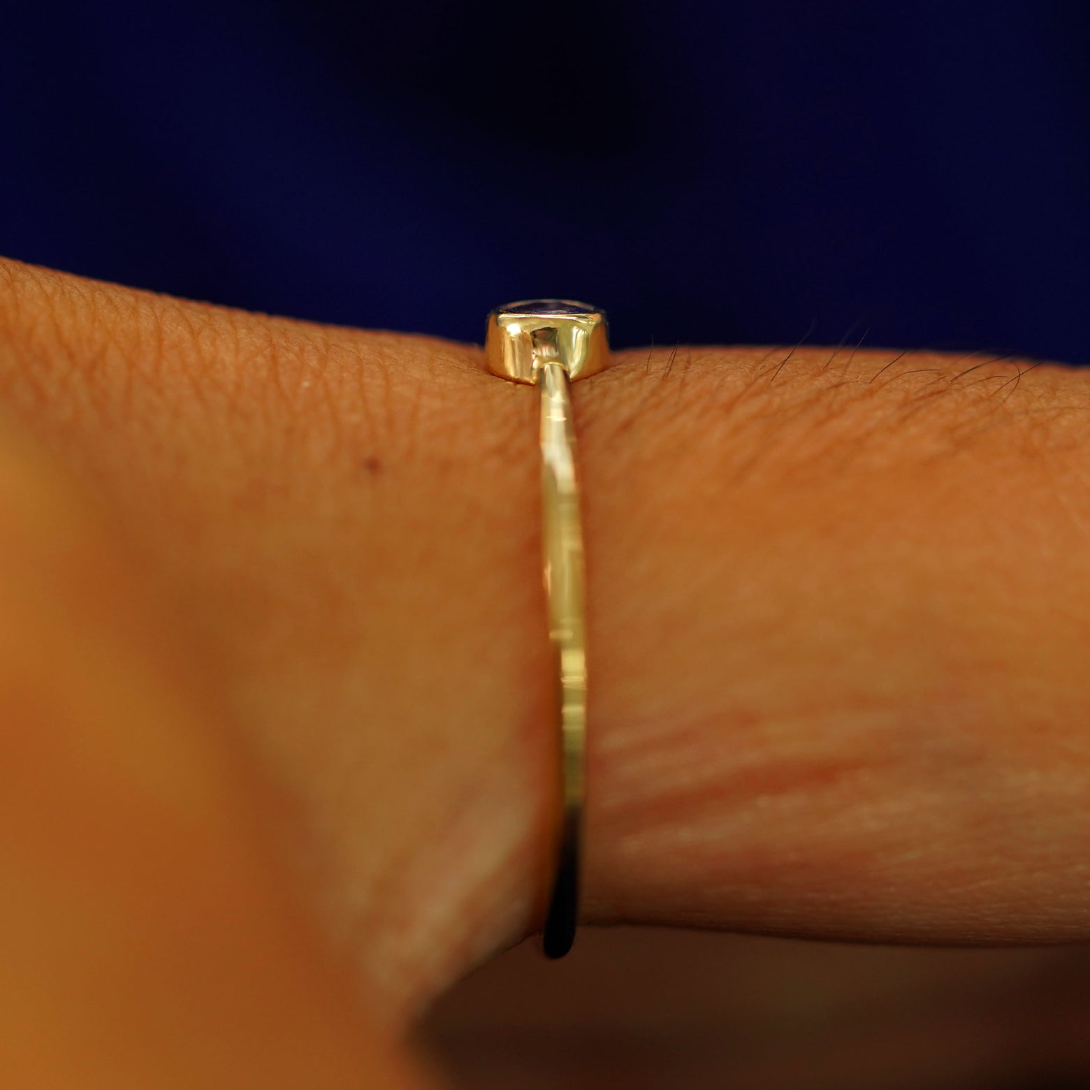 Side view of a solid gold Tanzanite Ring on a model's finger