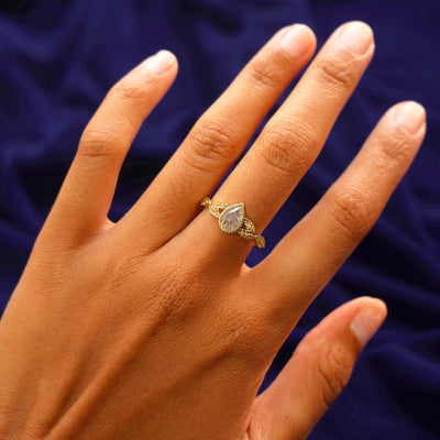 Close up view of a model's hand wearing a yellow gold Pear Salt and Pepper Diamond Leaves Ring