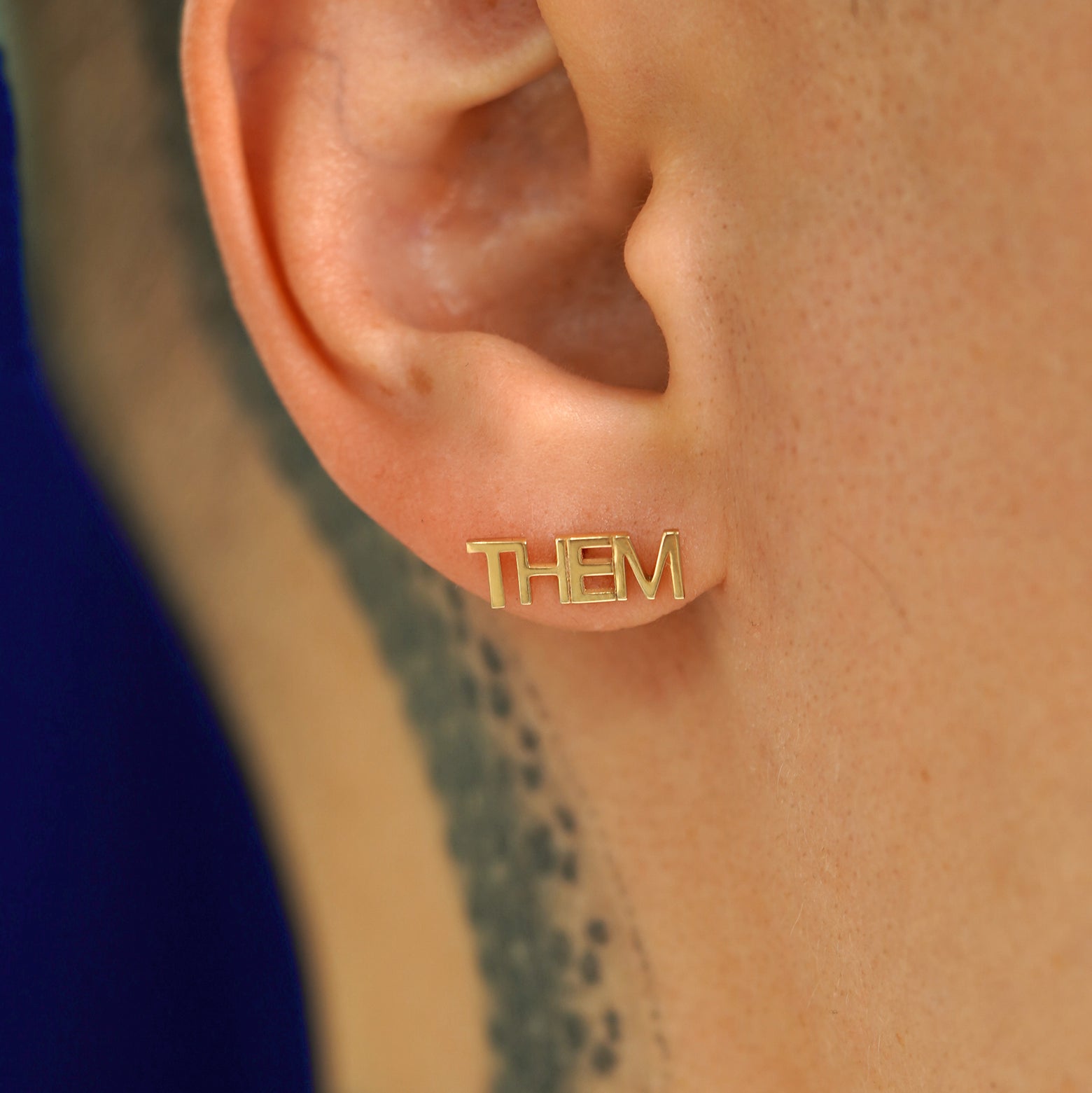 Close up view of a model's ear wearing a 14k gold Them Earring