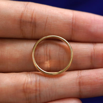 A yellow gold Beveled Edge Band in a model's hand showing the thickness of the band