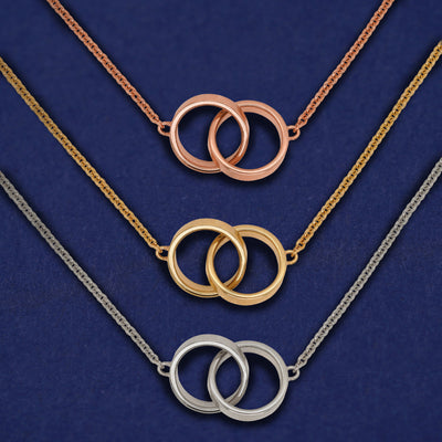 Three versions of the Bound Together Necklace shown in options of rose, yellow, and white gold