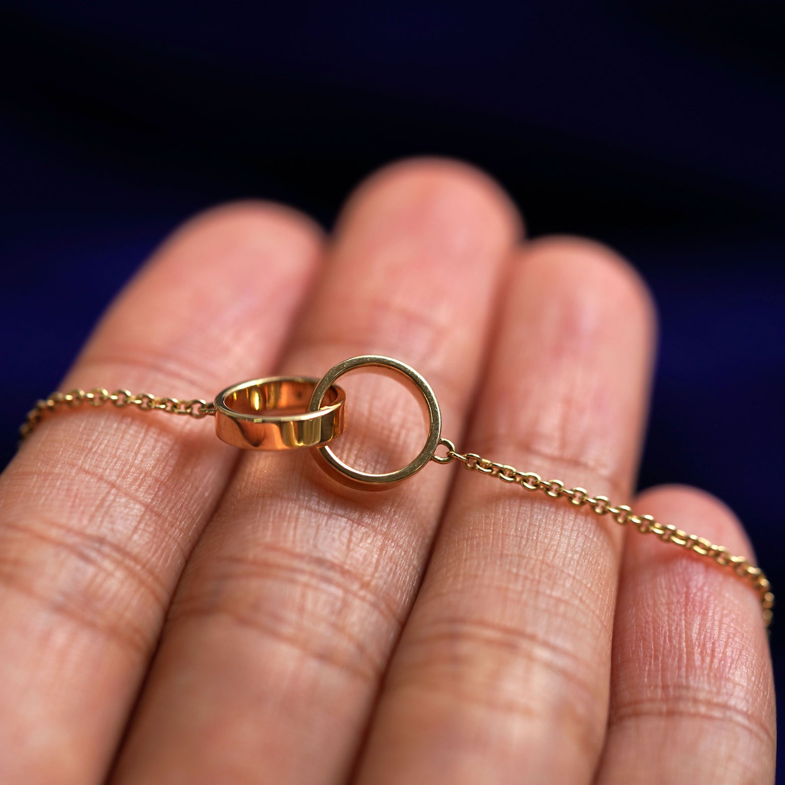 A yellow gold Bound Together Necklace resting on a model's fingers