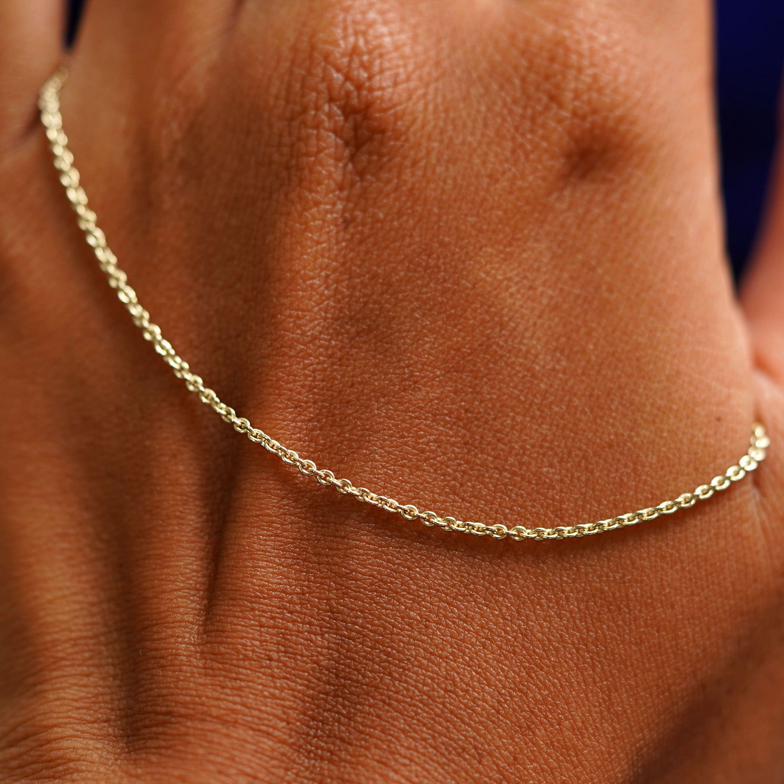 A solid gold Thick Cable Bracelet resting on the back of a model's hand